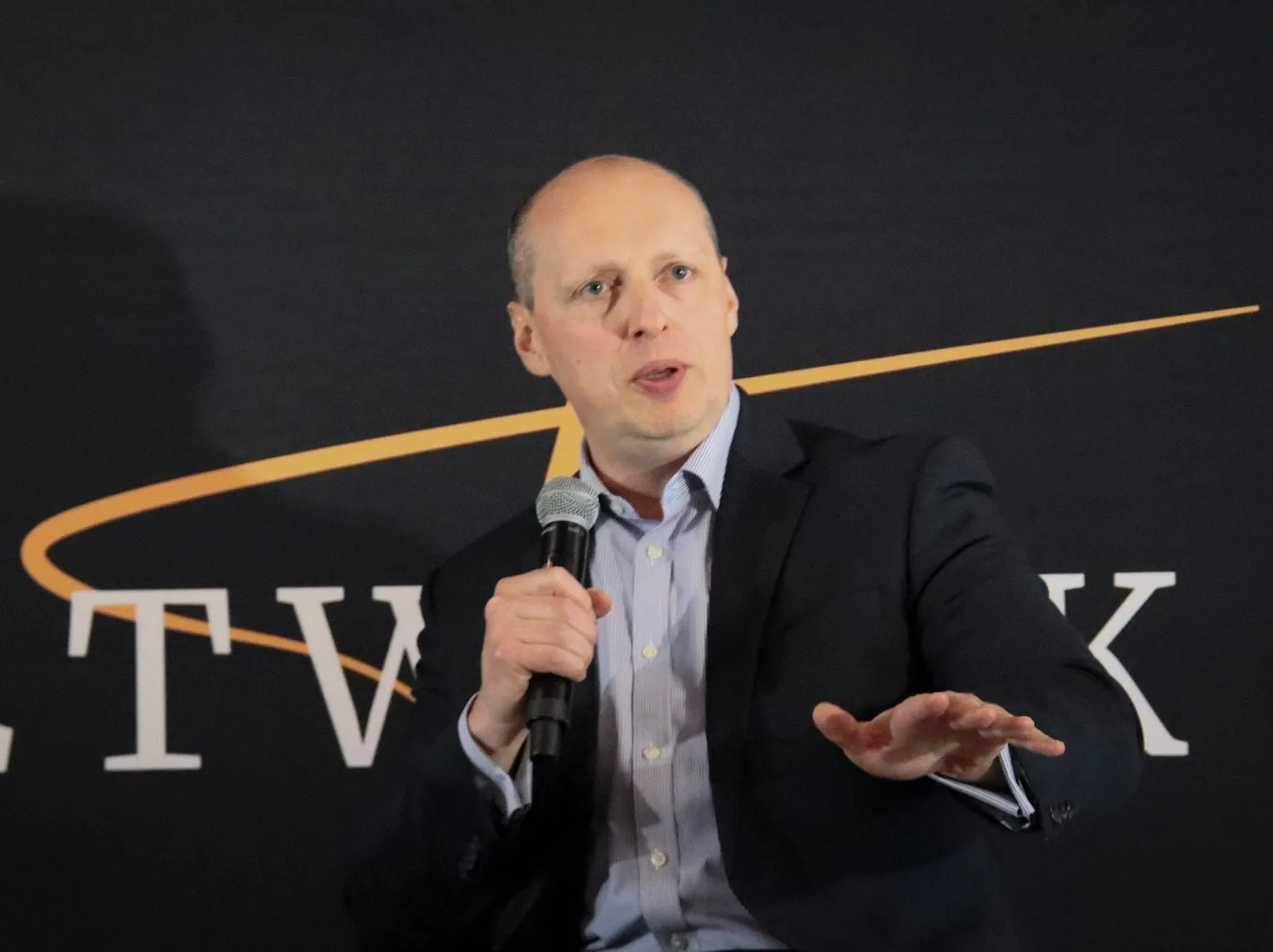 Yuriy Demidko mid-sentence with a microphone on the THEE Network stage in Detroit