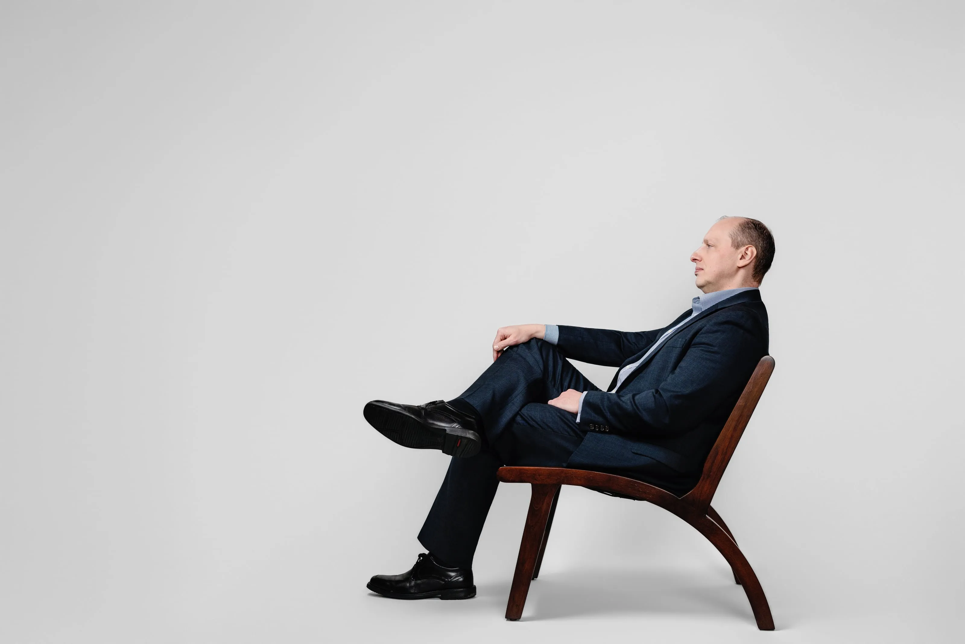 Yuriy Demidko seated in a low chair, in profile, thinking