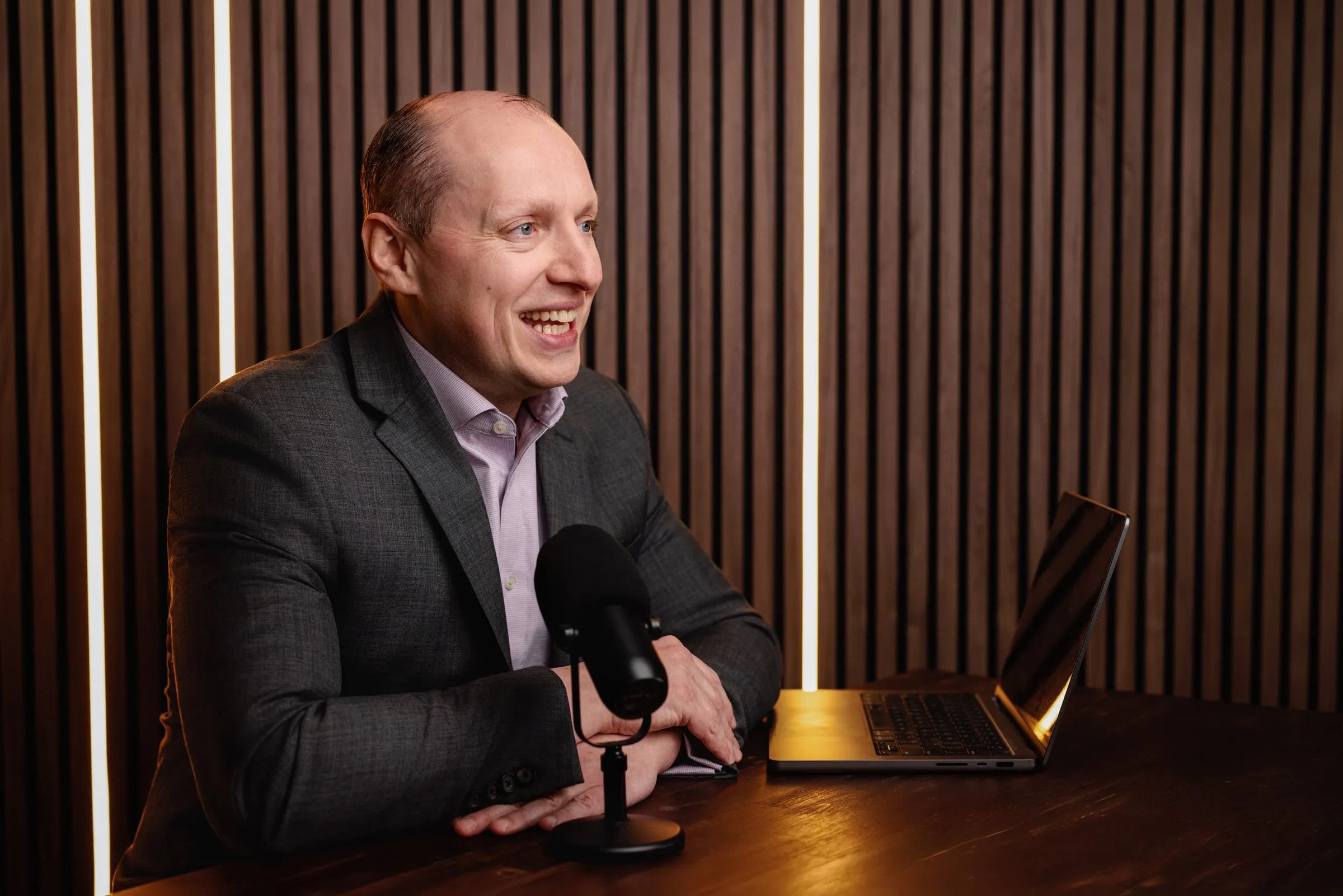 Yuriy Demidko in profile, laughing at a podcast microphone